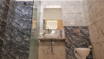 A bathroom with a glass shower enclosure, a white sink with a mirror above it, and a toilet.