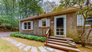 A small wooden cabin with a front door, two windows, and a set of wooden steps leading to a porch. - Mashpee Heaven Lake front (Mashpee)