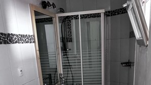 Un baño pequeño con lavadora, inodoro y zona de ducha.