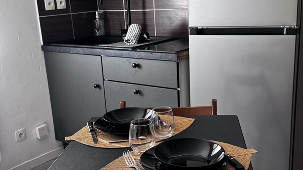 Cocina compacta con microondas, refrigerador y una mesa para dos.
