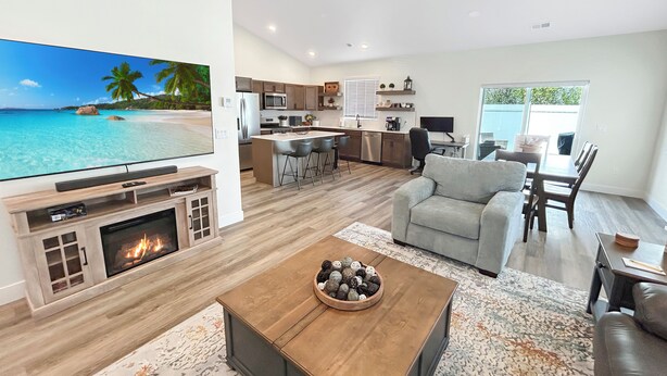 Een moderne woonkamer met een open haard, een televisie en een eethoek met uitzicht op de oceaan.