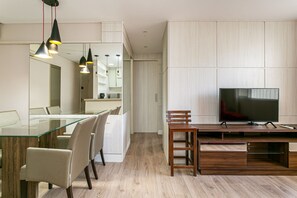 Una cocina moderna con mesa de comedor de vidrio, sillas de madera y lámparas colgantes.