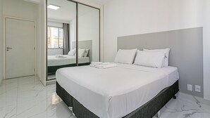 Ein modernes Schlafzimmer mit einem großen Bett, einem Schiebetürenschrank und Blick ins Freie.