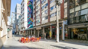 Eine Straße mit Außenbereich, einem farbenfrohen Wandgemälde und verschiedenen Geschäften.