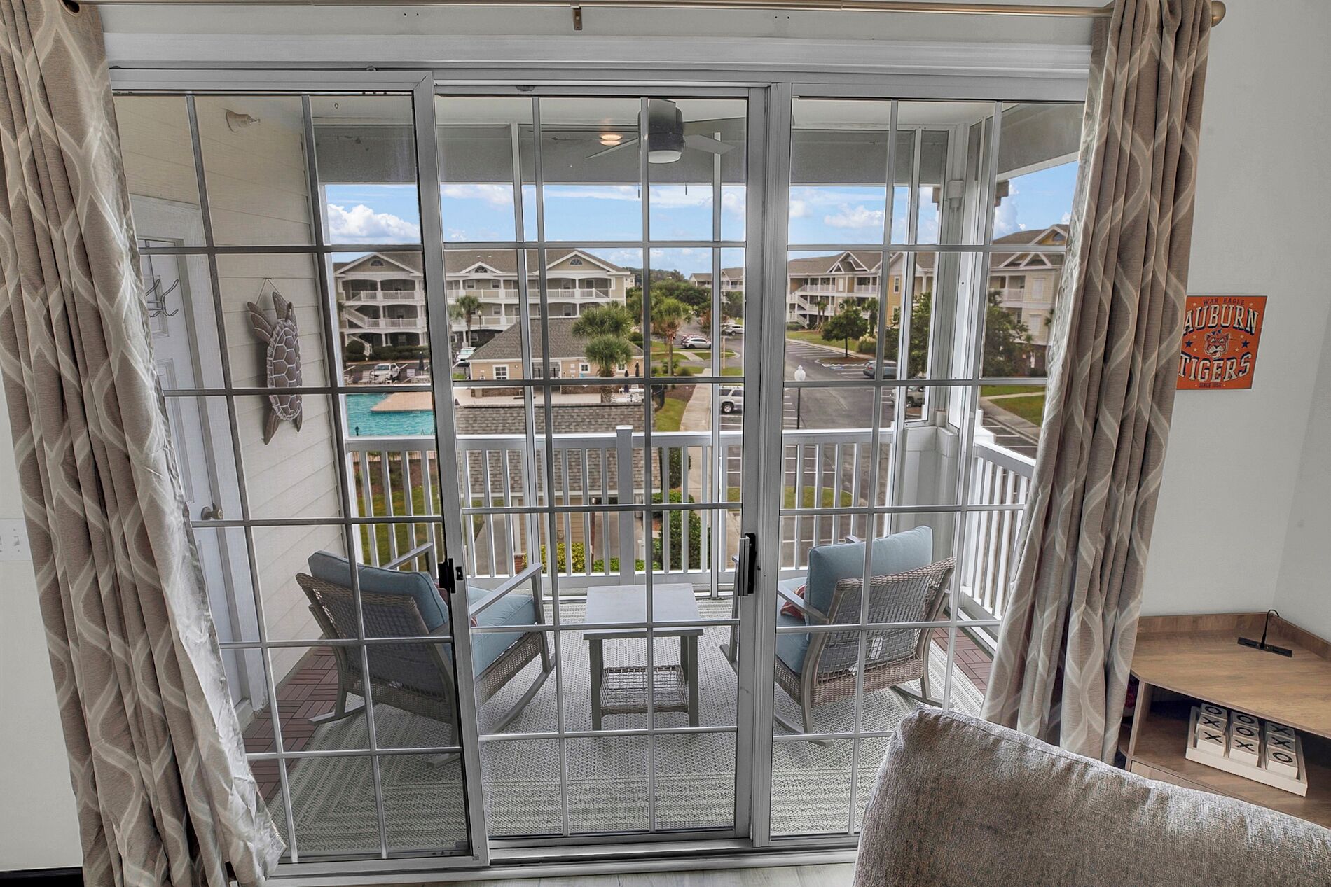 A balcony with a view of a residential area, including houses and a swimming pool.