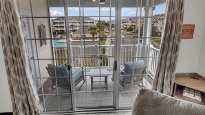A balcony with a view of a residential area, including houses and a swimming pool.