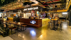 A modern bar with a neon sign, wooden tables, and a pizza counter. - Partial Sea View | Food Hall | Pool #CA78 (Florianópolis)