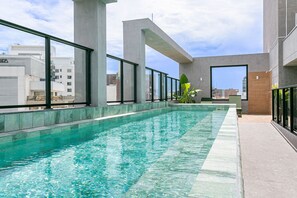 Una piscina en la azotea con agua cristalina, rodeada de amplias ventanas y pilares de hormigón.