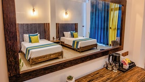 Ein Hotelzimmer mit zwei Betten, einem großen Spiegel, einer Holzkommode und einem Fenster mit Vorhängen.