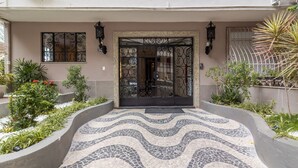 Una entrada empaveda con un camino curvo, puertas de metal decorativas y plantas en macetas.