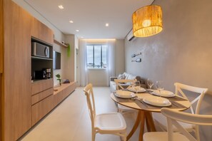A modern dining area with a wooden table set for four, white chairs, and a large window providing natural light.