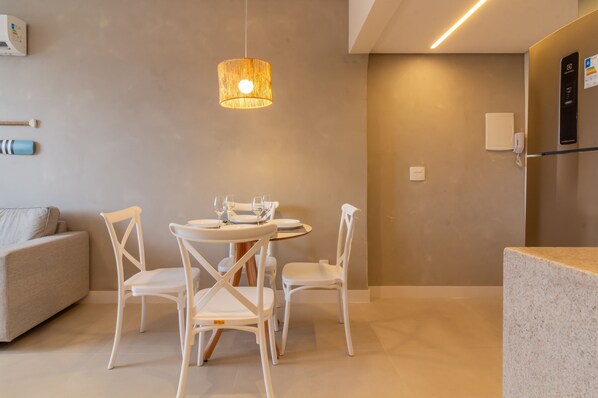 A modern dining area with a round table, white chairs, and a hanging light fixture.