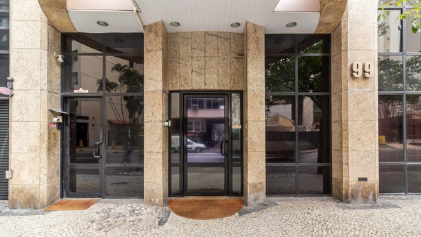 A building entrance with a glass door, a stone facade, and a tiled ground.