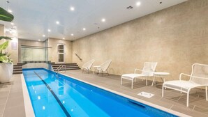 Une piscine bordée de chaises longues blanches et un escalier menant à un niveau supérieur.