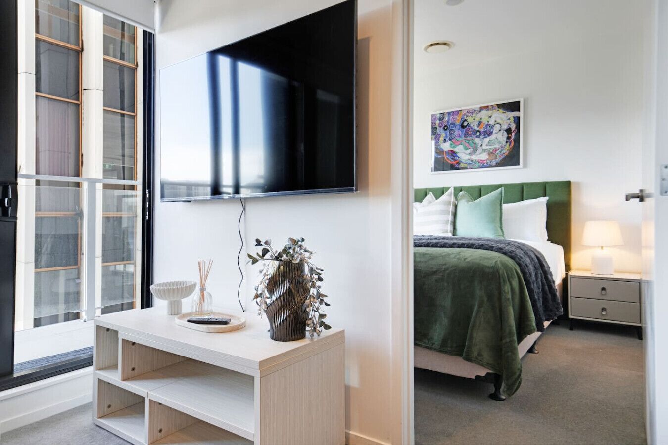 A modern bedroom with a bed, bedside table, and a TV mounted on the wall.