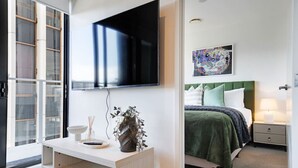 Une chambre à coucher moderne avec un lit, une table de chevet et un téléviseur fixé au mur.