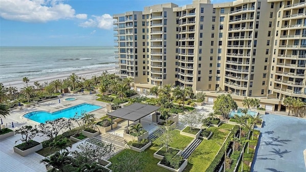 A hotel with a pool, outdoor seating, and a view of the ocean.