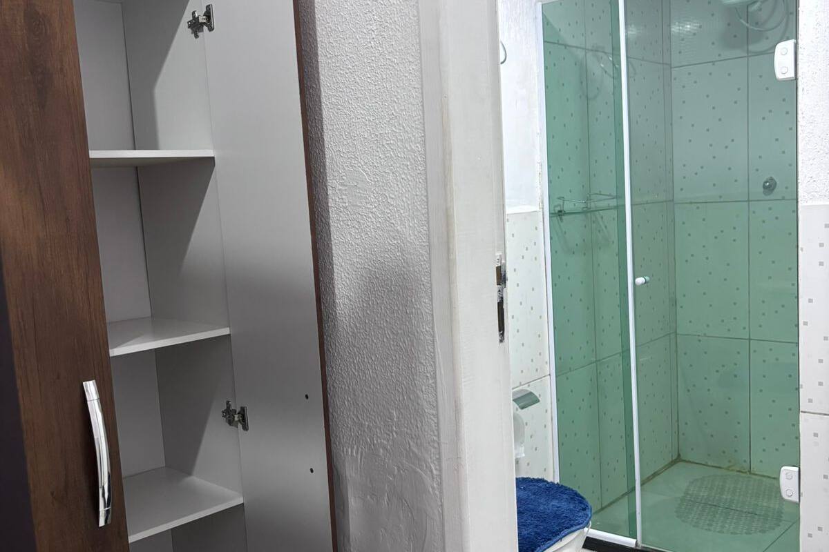 Un baño con ducha, un armario blanco y una alfombra azul.