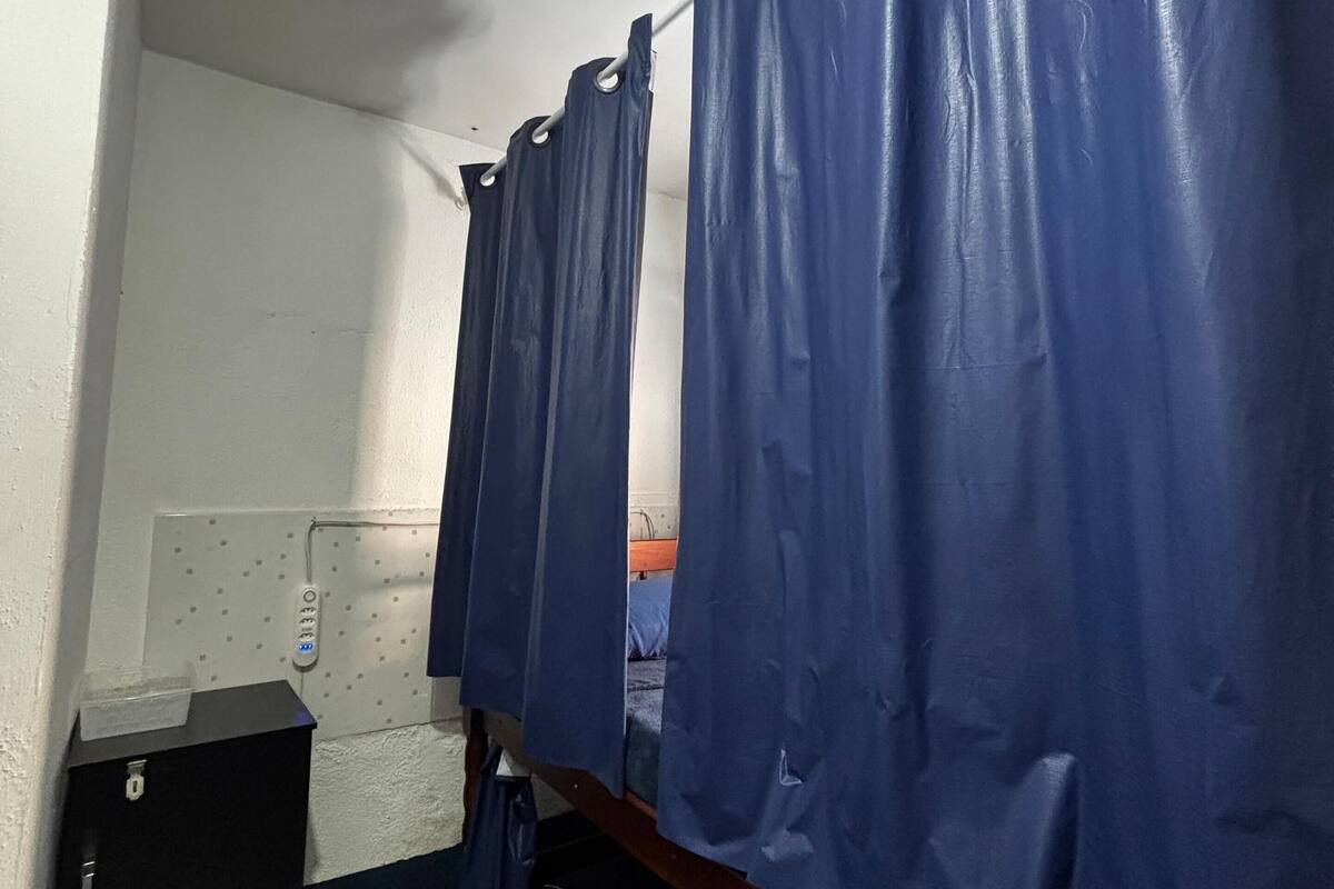 Una fila de cortinas azules en una habitación con una pared blanca y un pequeño mueble de madera.