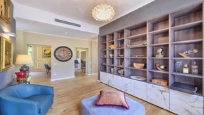 A spacious living room with a blue armchair, a marble fireplace, and a large bookshelf filled with decorative items. - Elegant Historic Villa with Pool, Jacuzzi & Lake Views in Lierna (Lierna)