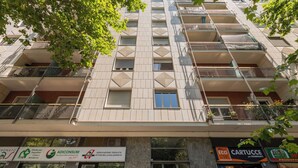 Un edificio de varios pisos con balcones, locales comerciales en la planta baja y una combinación de rótulos y anuncios.
