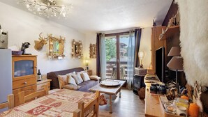 Uma sala de estar acolhedora com uma mesa de madeira, sofá e televisão.