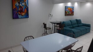 Uma área de refeições com uma mesa e cadeiras, um sofá azul e duas pinturas nas paredes.