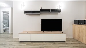 Un salon moderne doté d’un téléviseur à écran plat, d’étagères intégrées et d’un meuble en bois.