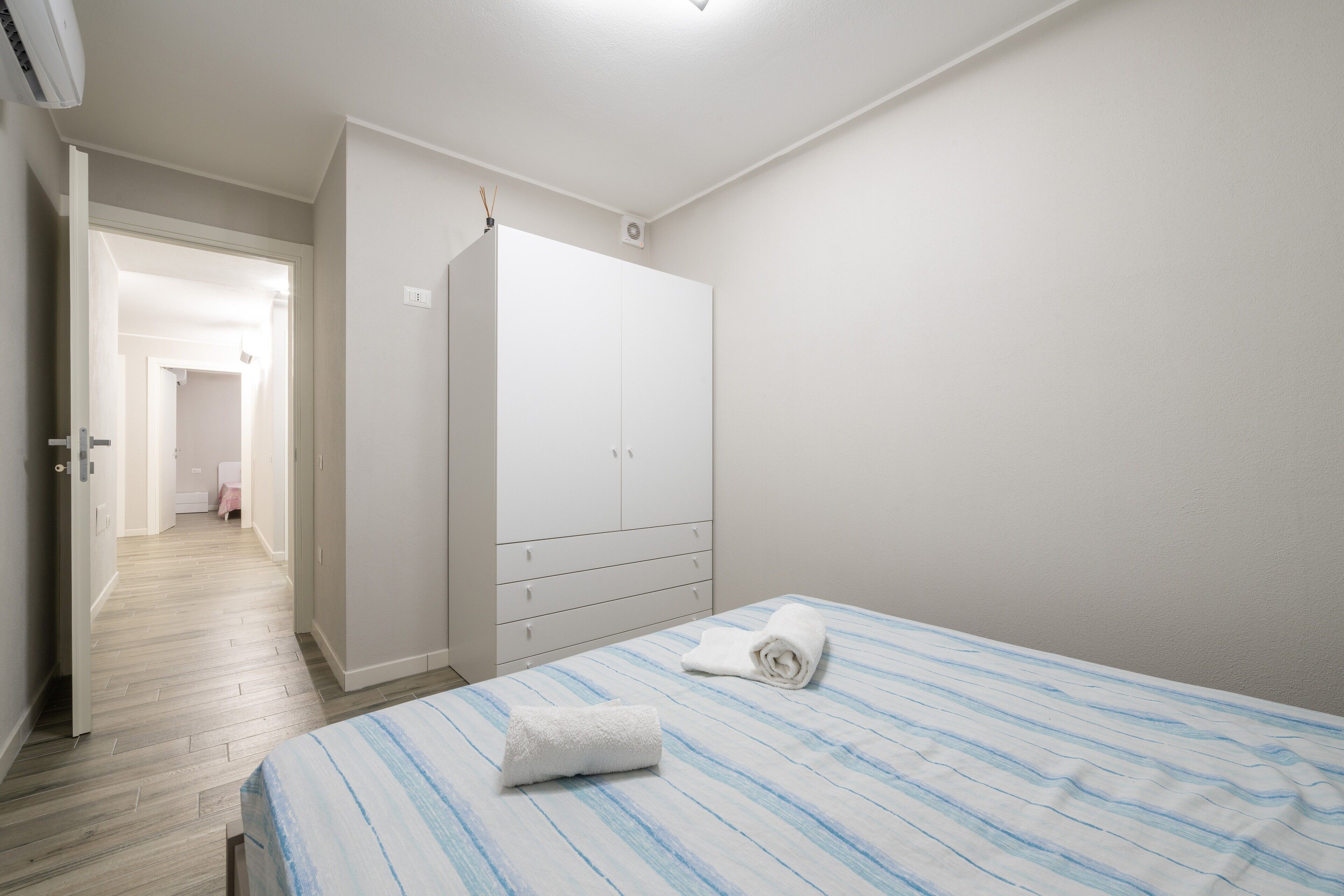 Ein Schlafzimmer mit einem Bett, einem Kleiderschrank und einem Flur, der in einen anderen Raum führt.