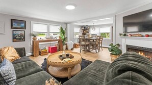 Un salón comedor amplio con chimenea, un área de comedor y una cocina al fondo.