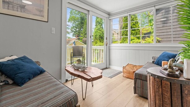 Una habitación acogedora con cama, una mesita y un banco. Amplias ventanas ofrecen vistas al exterior.