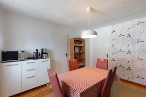 Cocina compacta con microondas, cafetera y un mueble de madera.