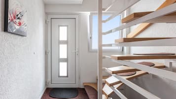 Ein modernes Interieur mit einer weißen Tür, einem kleinen Teppich und einer Holztreppe.