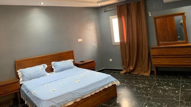 Ein Schlafzimmer mit Bett, Nachttischen, einem Schminktisch und einer Klimaanlage.