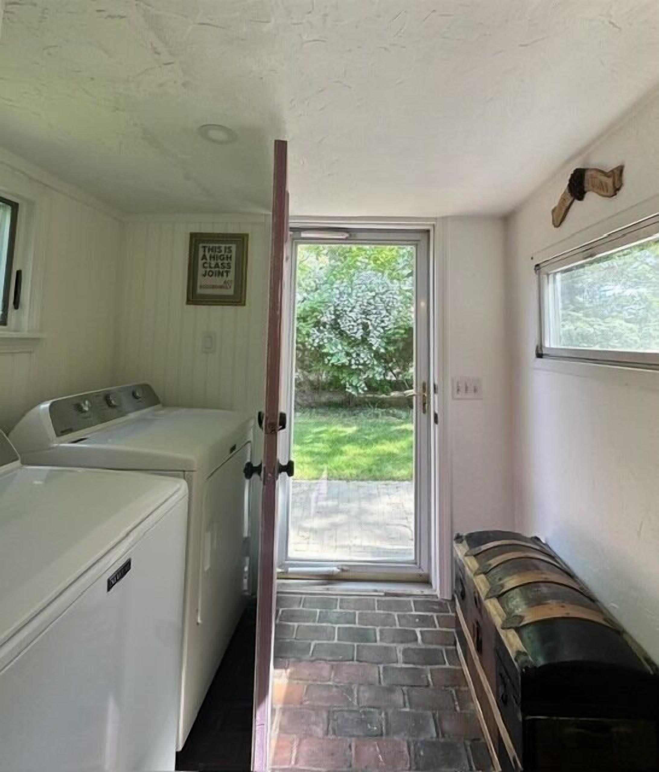 A laundry room with a washer and dryer, a door leading to a patio, and a fireplace.