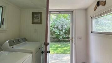A laundry room with a washer and dryer, a door leading to a patio, and a fireplace.