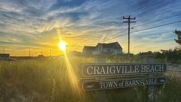 A sign for Craigville Beach, Town of Barnstable, with a sunset in the background.