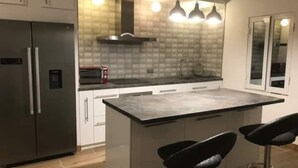 A modern kitchen with a large island, stainless steel appliances, and pendant lighting. - Bugibba apartment 50 Yards to sea bars & shops (San Pawl il-Baħar)