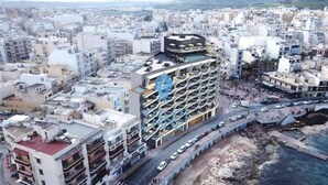 A multi-story hotel with a rooftop pool and a parking garage. - Bugibba apartment 50 Yards to sea bars & shops (San Pawl il-Baħar)