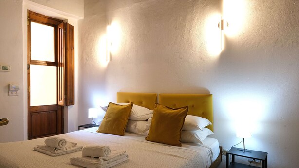 A neatly made bed with pillows, a bedside lamp, and a folded towel on the bed. - Wine Apartments Florence Sagrantino (Firenze)
