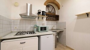 A compact kitchen with a gas stove, a microwave, a built-in oven, a sink, and a small refrigerator. - Wine Apartments Florence Sagrantino (Firenze)