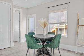 A dining area with a round table, four green chairs, and a vase with pampas grass. - Stunning Rooftop Deck Near Downtown Durham (Durham)