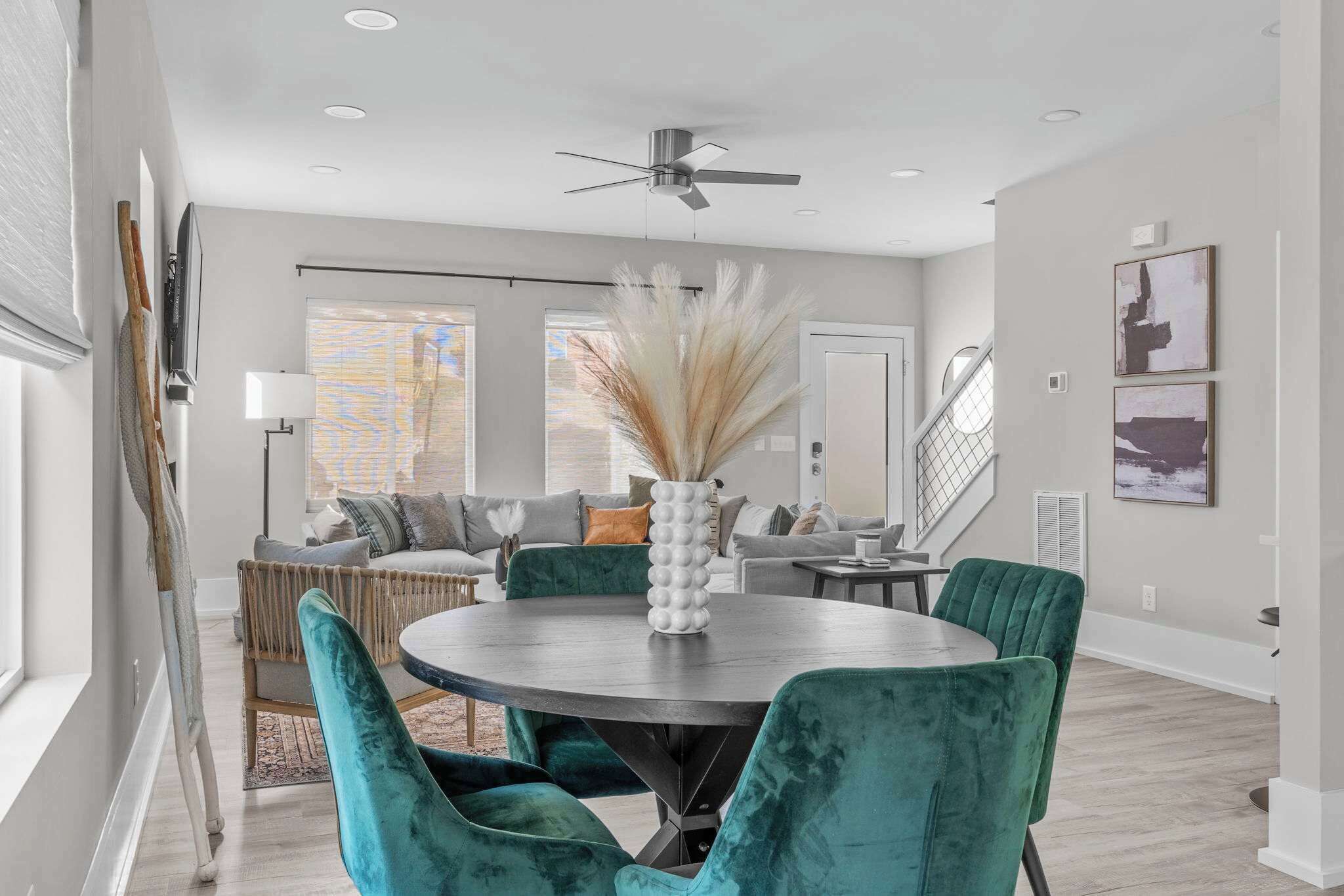 A modern dining area with a round table, teal chairs, and a decorative vase.