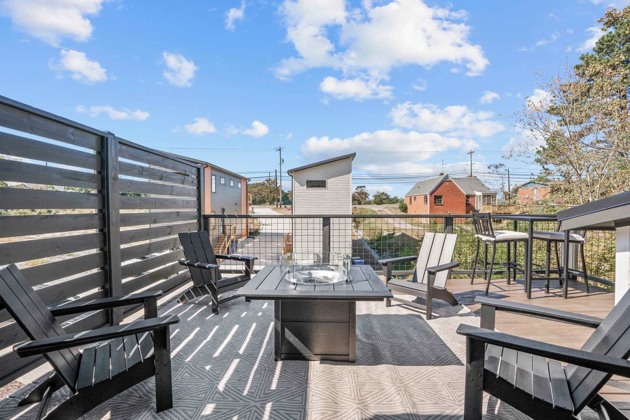 Un patio exterior con mesa y sillas, una chimenea y vistas a casas vecinas.