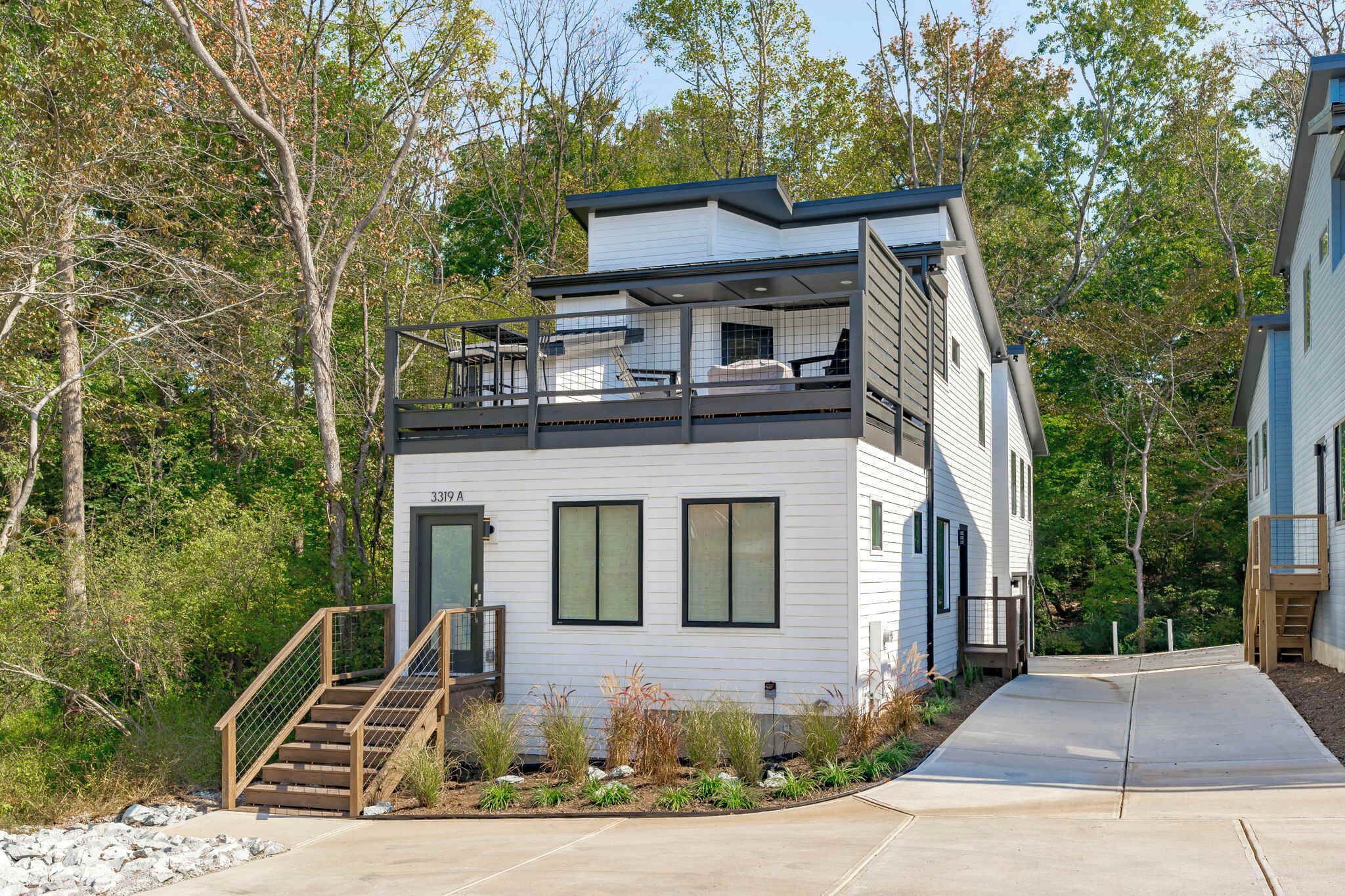 Een modern huis met twee verdiepingen, een balkon, een trap en een oprit.