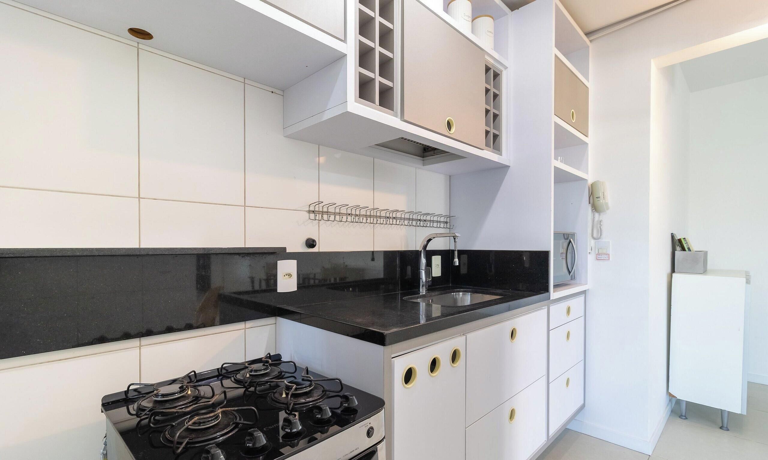 Une cuisine moderne avec des meubles blancs, un plan de travail noir et une cuisinière à gaz.