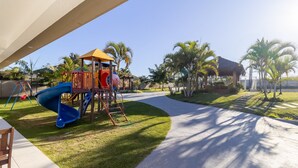 Une aire de jeux avec un toboggan, des balançoires et une structure d’escalade.
