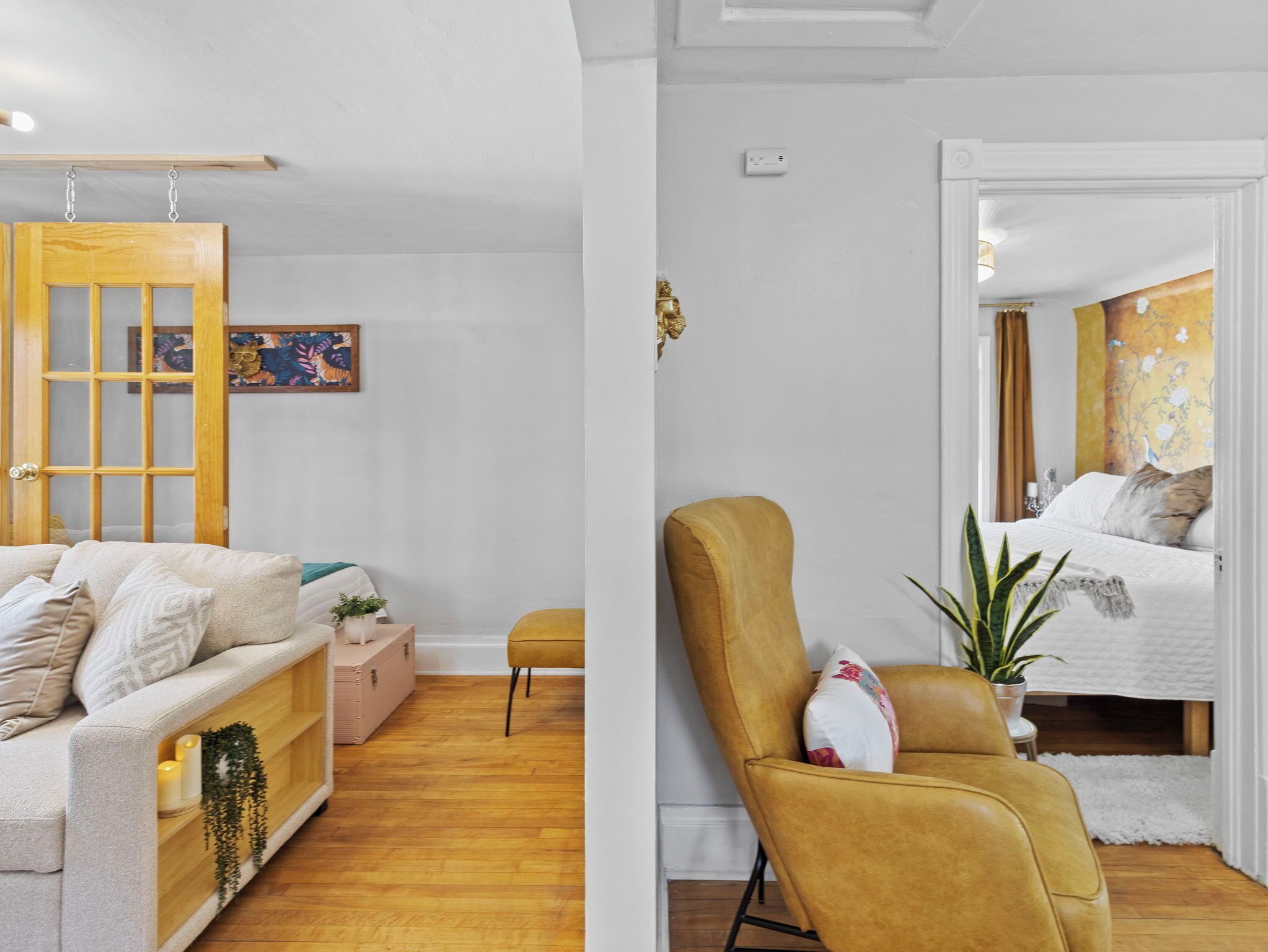 A modern living room with a sofa, a yellow armchair, a wooden door, and a small table with a plant.