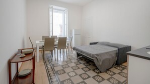Habitación pequeña con cama, escritorio y silla. Una ventana proporciona luz natural.