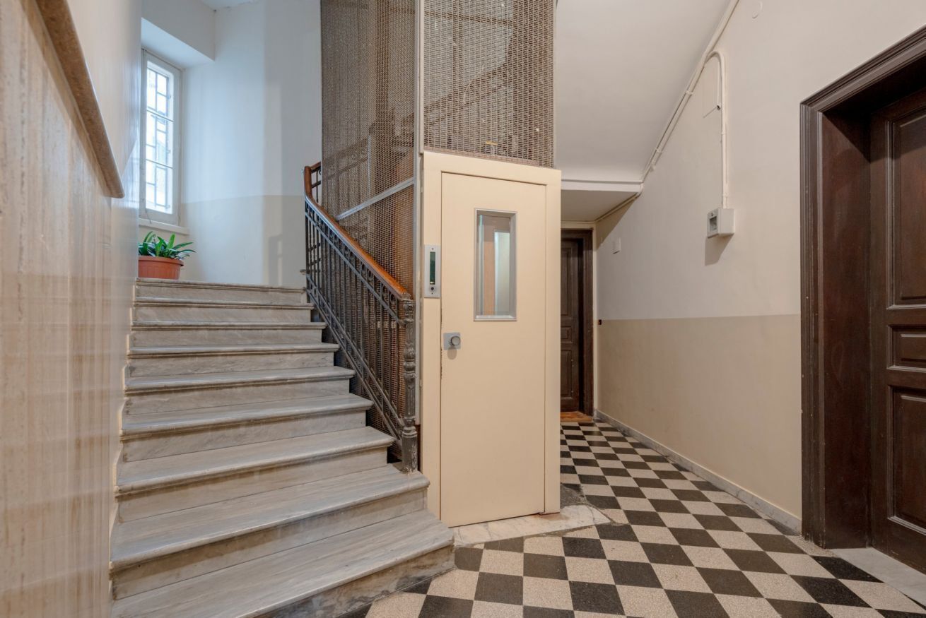 A staircase with a checkered floor, a door with a small window, and a potted plant.